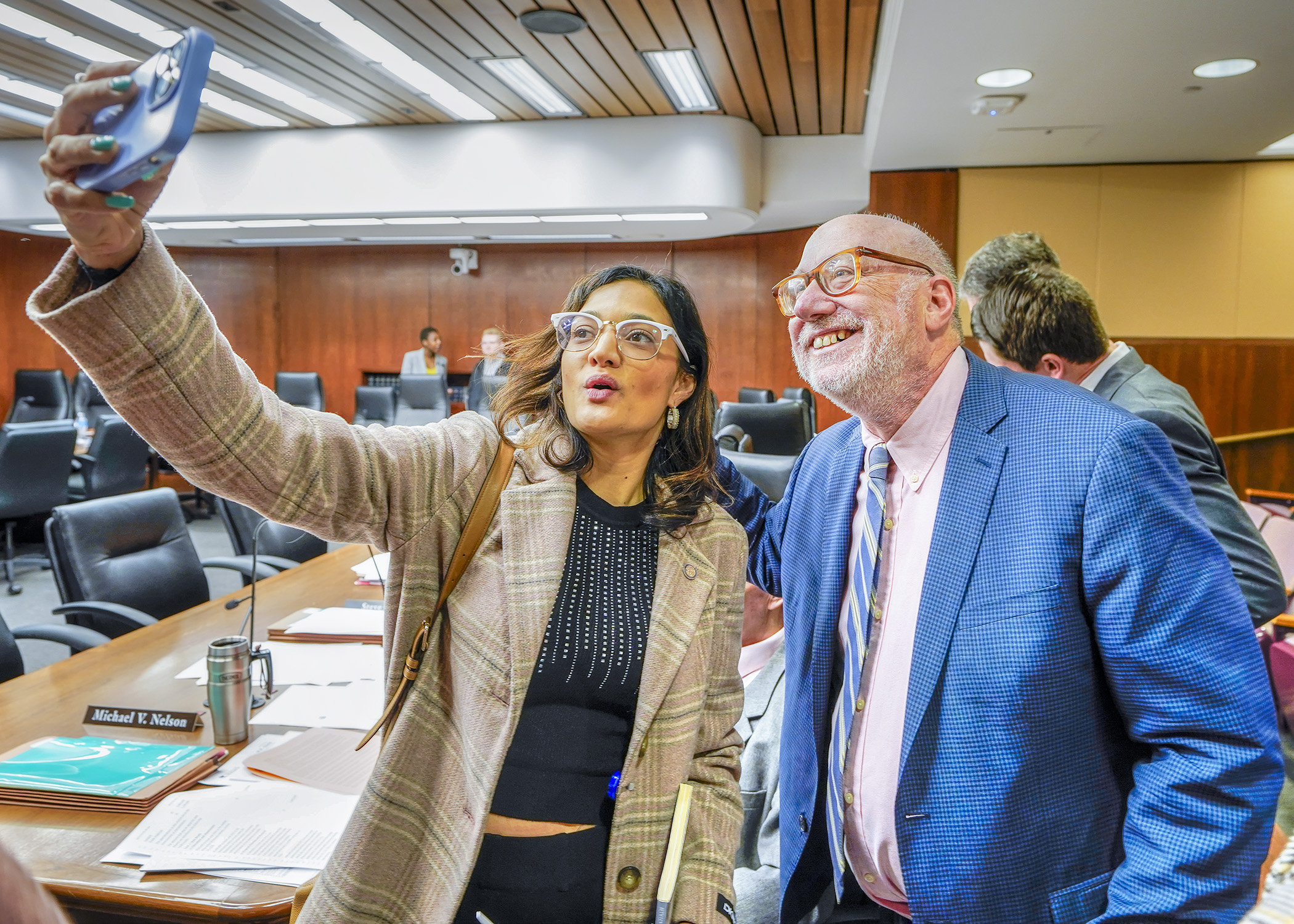 Rep. María Isa Pérez-Vega and Rep. Frank Hornstein take a selfie during an April 18 recess of the House Transportation Finance and Policy Committee to honor Hornstein, the committee chair, who is not seeking re-election. (Photo by Andrew VonBank)